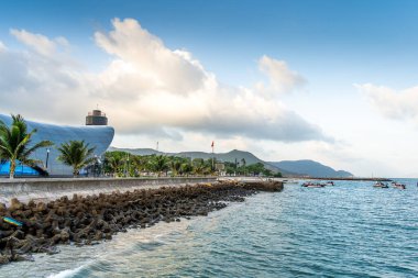 Con Son kasabasındaki yeni Con Dao yolcu limanının manzarası. Huzurlu bir Con Dao Adası, Vietnam. Dalgalı kıyı manzarası, kıyı şeridi, açık gökyüzü, mavi deniz, turistler ve dağ. Seyahat ve manzara konsepti.