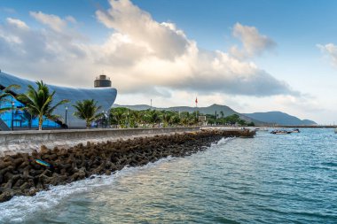 Con Son kasabasındaki yeni Con Dao yolcu limanının manzarası. Huzurlu bir Con Dao Adası, Vietnam. Dalgalı kıyı manzarası, kıyı şeridi, açık gökyüzü, mavi deniz, turistler ve dağ. Seyahat ve manzara konsepti.