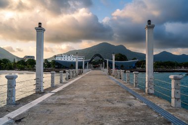 Con Son kasabasındaki yeni Con Dao yolcu limanının manzarası. Huzurlu bir Con Dao Adası, Vietnam. Dalgalı kıyı manzarası, kıyı şeridi, açık gökyüzü, mavi deniz, turistler ve dağ. Seyahat ve manzara konsepti.