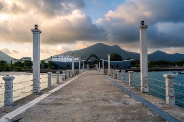 Con Son kasabasındaki yeni Con Dao yolcu limanının manzarası. Huzurlu bir Con Dao Adası, Vietnam. Dalgalı kıyı manzarası, kıyı şeridi, açık gökyüzü, mavi deniz, turistler ve dağ. Seyahat ve manzara konsepti.