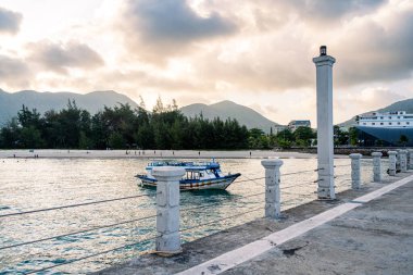 Con Son kasabasındaki yeni Con Dao yolcu limanının manzarası. Huzurlu bir Con Dao Adası, Vietnam. Dalgalı kıyı manzarası, kıyı şeridi, açık gökyüzü, mavi deniz, turistler ve dağ. Seyahat ve manzara konsepti.