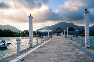 Con Son kasabasındaki yeni Con Dao yolcu limanının manzarası. Huzurlu bir Con Dao Adası, Vietnam. Dalgalı kıyı manzarası, kıyı şeridi, açık gökyüzü, mavi deniz, turistler ve dağ. Seyahat ve manzara konsepti.