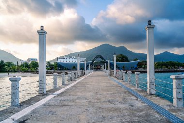 Con Son kasabasındaki yeni Con Dao yolcu limanının manzarası. Huzurlu bir Con Dao Adası, Vietnam. Dalgalı kıyı manzarası, kıyı şeridi, açık gökyüzü, mavi deniz, turistler ve dağ. Seyahat ve manzara konsepti.