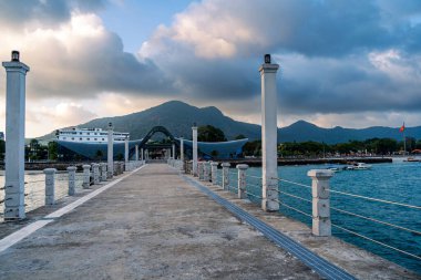 Con Son kasabasındaki yeni Con Dao yolcu limanının manzarası. Huzurlu bir Con Dao Adası, Vietnam. Dalgalı kıyı manzarası, kıyı şeridi, açık gökyüzü, mavi deniz, turistler ve dağ. Seyahat ve manzara konsepti.