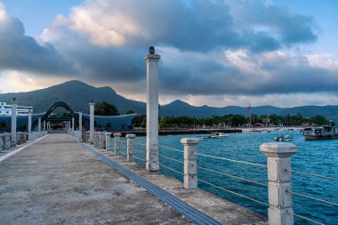 Con Son kasabasındaki yeni Con Dao yolcu limanının manzarası. Huzurlu bir Con Dao Adası, Vietnam. Dalgalı kıyı manzarası, kıyı şeridi, açık gökyüzü, mavi deniz, turistler ve dağ. Seyahat ve manzara konsepti.