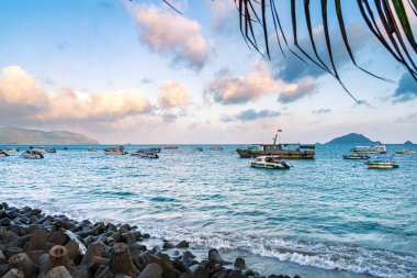 Con Son kasabasındaki yeni Con Dao yolcu limanının manzarası. Huzurlu bir Con Dao Adası, Vietnam. Dalgalı kıyı manzarası, kıyı şeridi, açık gökyüzü, mavi deniz, turistler ve dağ. Seyahat ve manzara konsepti.