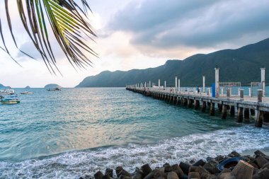 Con Son kasabasındaki yeni Con Dao yolcu limanının manzarası. Huzurlu bir Con Dao Adası, Vietnam. Dalgalı kıyı manzarası, kıyı şeridi, açık gökyüzü, mavi deniz, turistler ve dağ. Seyahat ve manzara konsepti.