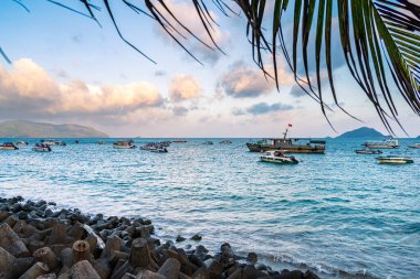 Con Son kasabasındaki yeni Con Dao yolcu limanının manzarası. Huzurlu bir Con Dao Adası, Vietnam. Dalgalı kıyı manzarası, kıyı şeridi, açık gökyüzü, mavi deniz, turistler ve dağ. Seyahat ve manzara konsepti.