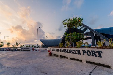 Con Son kasabasındaki yeni Con Dao yolcu limanının manzarası. Huzurlu bir Con Dao Adası, Vietnam. Dalgalı kıyı manzarası, kıyı şeridi, açık gökyüzü, mavi deniz, turistler ve dağ. Seyahat ve manzara konsepti.
