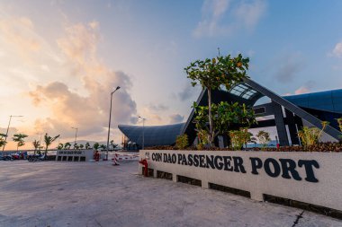 Con Son kasabasındaki yeni Con Dao yolcu limanının manzarası. Huzurlu bir Con Dao Adası, Vietnam. Dalgalı kıyı manzarası, kıyı şeridi, açık gökyüzü, mavi deniz, turistler ve dağ. Seyahat ve manzara konsepti.