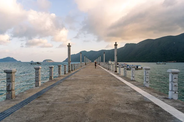 Con Son kasabasındaki yeni Con Dao yolcu limanının manzarası. Huzurlu bir Con Dao Adası, Vietnam. Dalgalı kıyı manzarası, kıyı şeridi, açık gökyüzü, mavi deniz, turistler ve dağ. Seyahat ve manzara konsepti.