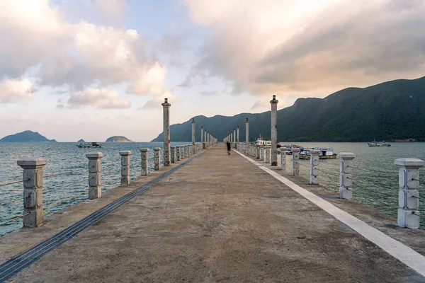 Con Son kasabasındaki yeni Con Dao yolcu limanının manzarası. Huzurlu bir Con Dao Adası, Vietnam. Dalgalı kıyı manzarası, kıyı şeridi, açık gökyüzü, mavi deniz, turistler ve dağ. Seyahat ve manzara konsepti.