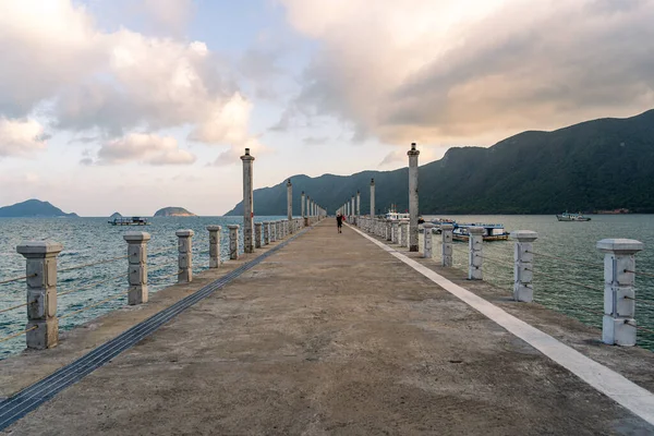 Con Son kasabasındaki yeni Con Dao yolcu limanının manzarası. Huzurlu bir Con Dao Adası, Vietnam. Dalgalı kıyı manzarası, kıyı şeridi, açık gökyüzü, mavi deniz, turistler ve dağ. Seyahat ve manzara konsepti.