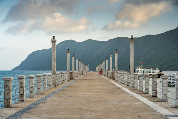 Con Son kasabasındaki yeni Con Dao yolcu limanının manzarası. Huzurlu bir Con Dao Adası, Vietnam. Dalgalı kıyı manzarası, kıyı şeridi, açık gökyüzü, mavi deniz, turistler ve dağ. Seyahat ve manzara konsepti.