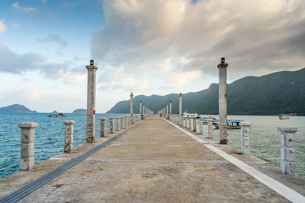 Con Son kasabasındaki yeni Con Dao yolcu limanının manzarası. Huzurlu bir Con Dao Adası, Vietnam. Dalgalı kıyı manzarası, kıyı şeridi, açık gökyüzü, mavi deniz, turistler ve dağ. Seyahat ve manzara konsepti.