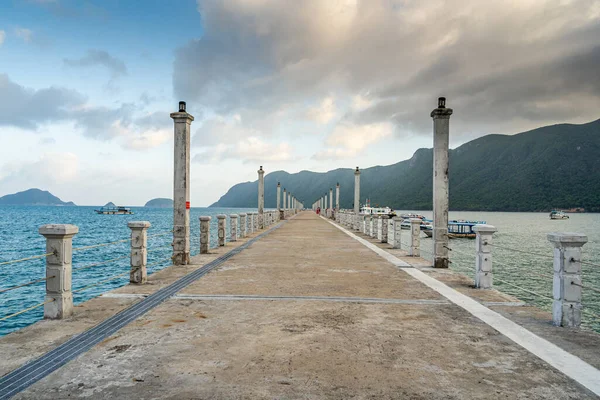 Con Son kasabasındaki yeni Con Dao yolcu limanının manzarası. Huzurlu bir Con Dao Adası, Vietnam. Dalgalı kıyı manzarası, kıyı şeridi, açık gökyüzü, mavi deniz, turistler ve dağ. Seyahat ve manzara konsepti.