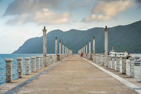 Con Son kasabasındaki yeni Con Dao yolcu limanının manzarası. Huzurlu bir Con Dao Adası, Vietnam. Dalgalı kıyı manzarası, kıyı şeridi, açık gökyüzü, mavi deniz, turistler ve dağ. Seyahat ve manzara konsepti.