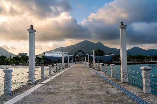 Con Son kasabasındaki yeni Con Dao yolcu limanının manzarası. Huzurlu bir Con Dao Adası, Vietnam. Dalgalı kıyı manzarası, kıyı şeridi, açık gökyüzü, mavi deniz, turistler ve dağ. Seyahat ve manzara konsepti.