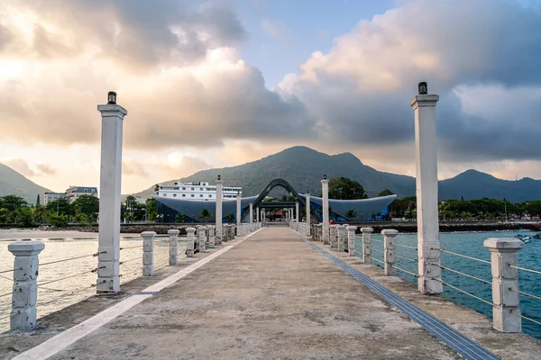 Con Son kasabasındaki yeni Con Dao yolcu limanının manzarası. Huzurlu bir Con Dao Adası, Vietnam. Dalgalı kıyı manzarası, kıyı şeridi, açık gökyüzü, mavi deniz, turistler ve dağ. Seyahat ve manzara konsepti.