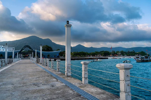 Con Son kasabasındaki yeni Con Dao yolcu limanının manzarası. Huzurlu bir Con Dao Adası, Vietnam. Dalgalı kıyı manzarası, kıyı şeridi, açık gökyüzü, mavi deniz, turistler ve dağ. Seyahat ve manzara konsepti.