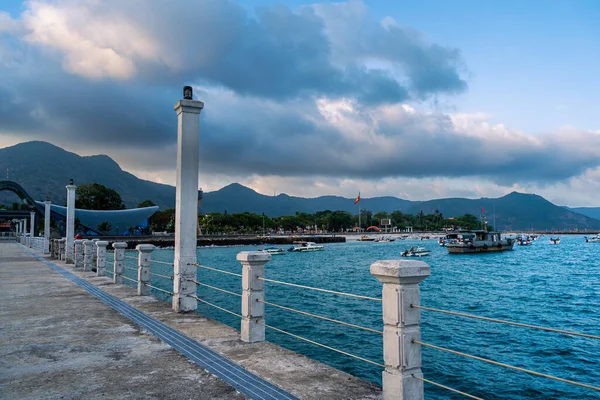 Con Son kasabasındaki yeni Con Dao yolcu limanının manzarası. Huzurlu bir Con Dao Adası, Vietnam. Dalgalı kıyı manzarası, kıyı şeridi, açık gökyüzü, mavi deniz, turistler ve dağ. Seyahat ve manzara konsepti.