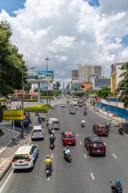 Ho Chi Minh şehri, Vietnam - 12 Ağustos 2023: Güneşli bir günde yoğun trafik ve Saygon caddesinde sayısız otel, bar ve dükkan tabelası bulunan renkli perspektif, insanlarla dolu, motosikletler