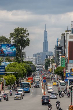 Ho Chi Minh şehri, Vietnam - 12 Ağustos 2023: Güneşli bir günde yoğun trafik ve Saygon caddesinde sayısız otel, bar ve dükkan tabelası bulunan renkli perspektif, insanlarla dolu, motosikletler