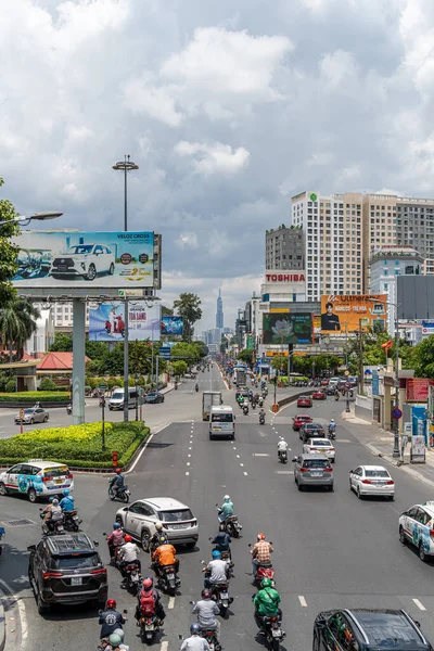 Ho Chi Minh şehri, Vietnam - 12 Ağustos 2023: Güneşli bir günde yoğun trafik ve Saygon caddesinde sayısız otel, bar ve dükkan tabelası bulunan renkli perspektif, insanlarla dolu, motosikletler