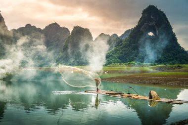 Tra Linh, Cao Bang vilayetindeki Thung Dağı 'nda nehirde balık tutan balıkçıları göl, bulutlu, doğa ile Vietnam' da görüyoruz. Seyahat ve manzara konsepti.