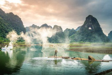 Tra Linh, Cao Bang vilayetindeki Thung Dağı 'nda nehirde balık tutan balıkçıları göl, bulutlu, doğa ile Vietnam' da görüyoruz. Seyahat ve manzara konsepti.