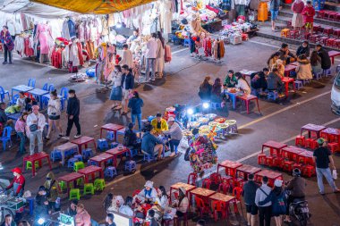 Dalat City, Vietnam - 01 Aralık 2023: Da Lat pazarında gece trafiği. Kalabalık atmosfer, soğuk havada sokak yemekleriyle beslenen gezginler, pazar yerinde kalabalık.