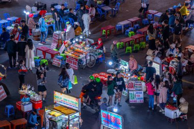 Dalat City, Vietnam - 01 Aralık 2023: Da Lat pazarında gece trafiği. Kalabalık atmosfer, soğuk havada sokak yemekleriyle beslenen gezginler, pazar yerinde kalabalık.