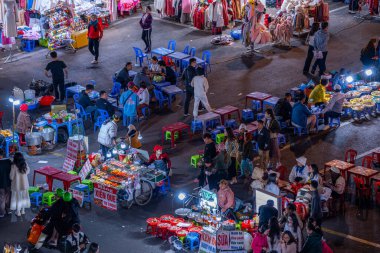 Dalat City, Vietnam - 01 Aralık 2023: Da Lat pazarında gece trafiği. Kalabalık atmosfer, soğuk havada sokak yemekleriyle beslenen gezginler, pazar yerinde kalabalık.