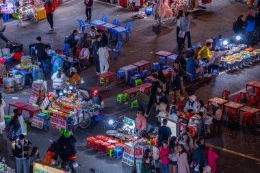 Dalat City, Vietnam - 01 Aralık 2023: Da Lat pazarında gece trafiği. Kalabalık atmosfer, soğuk havada sokak yemekleriyle beslenen gezginler, pazar yerinde kalabalık.