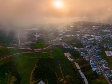 Sabahleyin, Da Lat şehri, Cau Dat, Lam Dong 'da güzel bir manzara. Çay tepesinde rüzgar enerjisi, çayın yamacında sabah manzarası güzel vadinin altındaki sisli dağlarda ekilmiş.