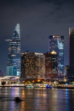 Ho Chi Minh şehri, Vietnam - 02 Ağustos 2023: Ho Chi Minh Şehri ufuk çizgisi ve Saigon Nehri. Şehir merkezindeki gökdelen ve diğer modern binaların inanılmaz renkli gece manzarası. Seyahat kavramı
