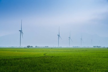 Türbin yeşil enerji elektriği, elektrik üretimi için yel değirmeni, Phan Rang, Ninh Thuan, Vietnam 'da pirinç tarlasında elektrik üreten rüzgar türbinleri. Temiz enerji kavramı.