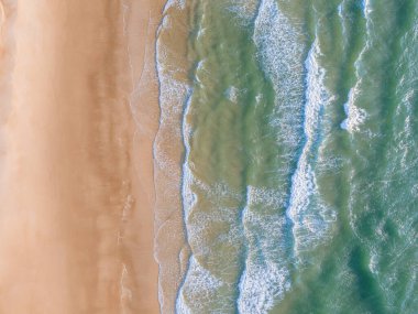 Sahildeki okyanus dalgaları arka planda kalıyor. Mavi su dalgalarıyla deniz ve sahilin yukarıdan görünüşü. Vietnam 'da güzel bir yaz tatili geçmişi var. Vietnam plajı