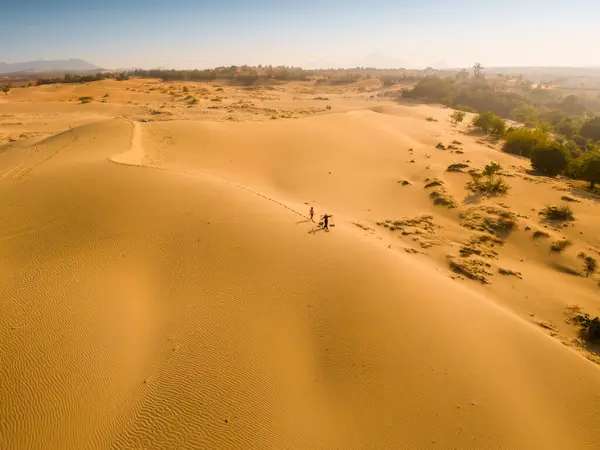 stock image Aerial view of a peasant woman carries a bamboo frame on the shoulder across sand dunes in Ninh Thuan province, Vietnam. It is one of the most beautiful places in Vietnam for travel and photography