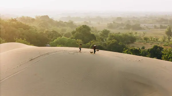 stock image Aerial view of a peasant woman carries a bamboo frame on the shoulder across sand dunes in Ninh Thuan province, Vietnam. It is one of the most beautiful places in Vietnam for travel and photography