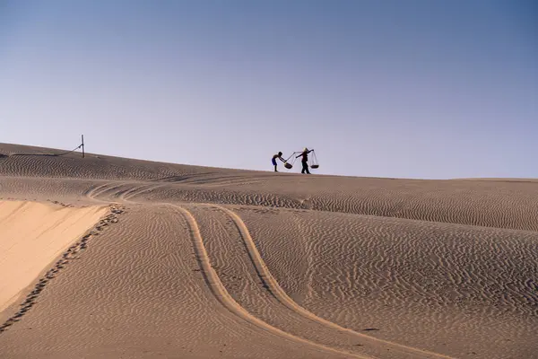 stock image Aerial view of a peasant woman carries a bamboo frame on the shoulder across sand dunes in Ninh Thuan province, Vietnam. It is one of the most beautiful places in Vietnam for travel and photography