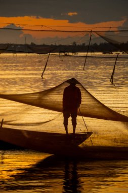 Kimliği belirlenemeyen balıkçı, ağlarını Hoi Nehri 'nde kontrol ediyor. Antik bir kasaba, Quang Nam Vilayeti, Vietnam. Hoi An, Vietnam 'daki en popüler yerlerden biridir. Seyahat kavramı