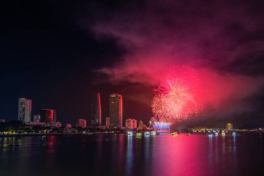 Da Nang şehri, Vietnam - 13 Temmuz 2024: Vietnam 'da Han nehri üzerinde havai fişeklerle gökyüzü aydınlandı. Güzel gece manzaralı şehir manzarası. Tatiller, yeni yılı ve Tet tatilini kutlamak.