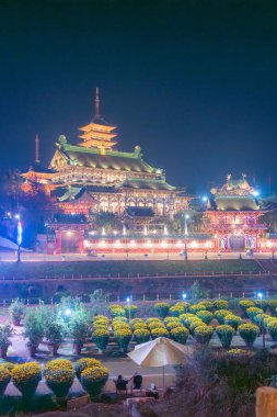 Aerial night view of Minh Thanh pagoda, a majestic Buddhist architectural structure in Pleiku city, Gia Lai province, Vietnam, text in photo mean Peace, Happy New Year. Travel concept. clipart