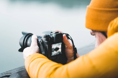 Close up view of male photographer using the rear lcd screen to compose and take a landscape photo with his digital camera dsrl using live view.