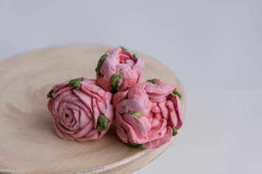 On a wooden round background lie natural marshmallows in the form of pinkroses flowers. Sweet desserts without sugar. Creative baking confectioners. Copy space, mock up. Sweet food