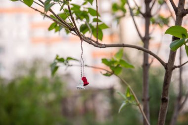 Symbol of the first day of spring Martisor. Tradition of giving red and white souvenir. At the end of March, Martisor is hung on a tree branch and wishes are made. Green natural background, Copy Space