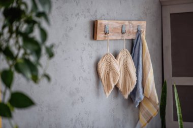 Macrame leaves hangs on a gray plain background. Handmade hobby. Decoration in Boho style. Scandinavian apartment interior. Trendy design details. Beige twine for weaving. Copy space. Mock up texture