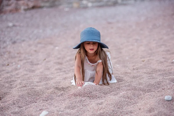 Little Girl Blue Hat White Dress Plays Sand Small Pebbles — Stockfoto