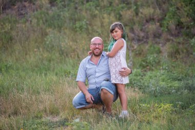 Gözlüklü kel baba yeşil saçlı kızı kucaklıyor. Çeşitlilik aile portresi gülümsüyor. Babalar Günü. Bakım, çocuk bakımı. Çocuk Koruma Günü. Bekar bir ebeveyn. Seyahat, tatil hafta sonu